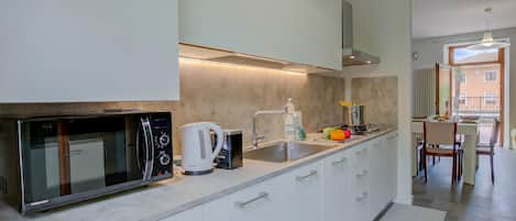 A modern kitchen with a built-in microwave, kettle, and sink.