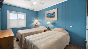 A room with two beds, a ceiling fan, a window with blinds, and a framed picture on the wall. - Three Bedroom Oceanside Condo Steps from the Beach (Ocean City)