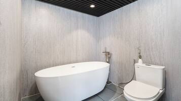 A modern bathroom with a freestanding bathtub, a toilet, and a shower.