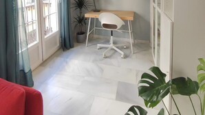 A room with a desk, chair, potted plants, and artwork on the wall.