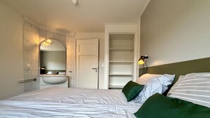 A bedroom with a bed, a bedside table, a mirror, a sink, and a wardrobe. - Nice apartment for 6 guests with WIFI, TV and terrace (Veere)