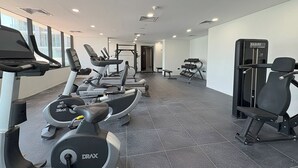 A modern gym with various exercise equipment, including treadmills, weight machines, and a bench. - Bloomfeilds Tranquil STU Al Maryah Vista (Abu Dhabi)