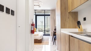 A modern hotel room with a kitchen, a balcony with a city view, and a bed with a view. - Bloomfeilds Tranquil STU Al Maryah Vista (Abu Dhabi)