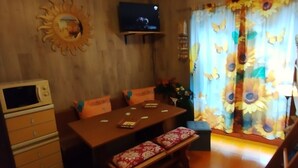 A dining area with a wooden table, benches, and a television mounted on the wall. - HOLIDAY HOUSE "SUN BEAM OF THE ALPS" The ideal apartment for your vacation (Montoso)