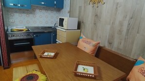 A compact kitchen with blue cabinets, a microwave, and a stove. There is a wooden dining table with two baskets and a sunflower decoration. - HOLIDAY HOUSE "SUN BEAM OF THE ALPS" The ideal apartment for your vacation (Montoso)