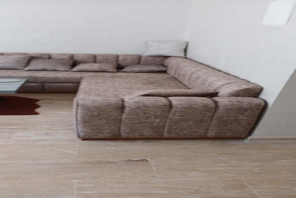 A corner sofa with a matching armchair, a small table, and a brown rug.