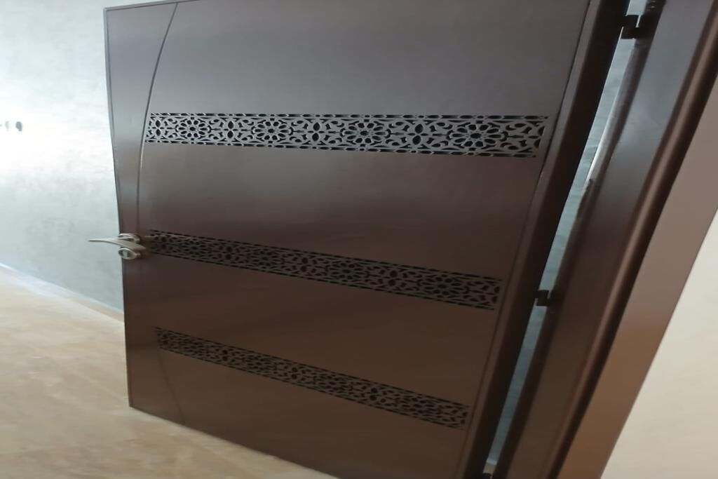 A closed door with a metallic handle and decorative cut-out patterns.