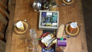 Une table de salle à manger en bois, sur laquelle sont disposés divers aliments pour le petit-déjeuner, notamment des fruits, du pain et des boissons.