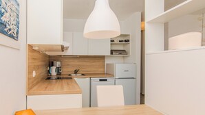 A modern kitchen with a wooden countertop, white cabinets, a white sink, and a built-in dishwasher. - Holiday home Korbar (Vir)