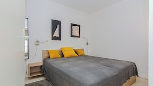 A bedroom with a bed, a nightstand, and a wall-mounted lamp. - Holiday home Korbar (Vir)