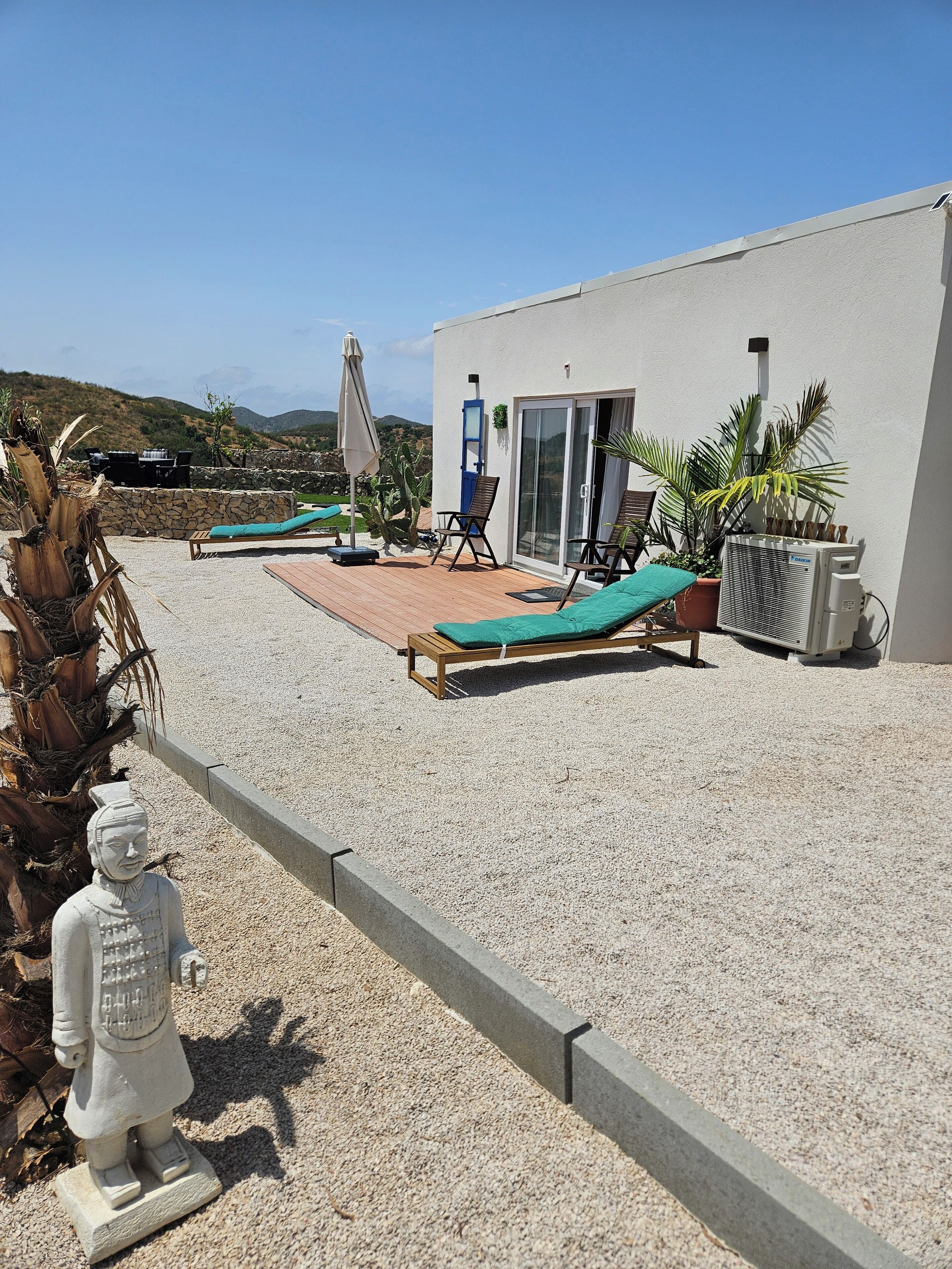 Un patio con tumbonas, un muro de piedra y una estatua.