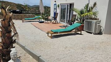 Un patio con tumbonas, un muro de piedra y una estatua.