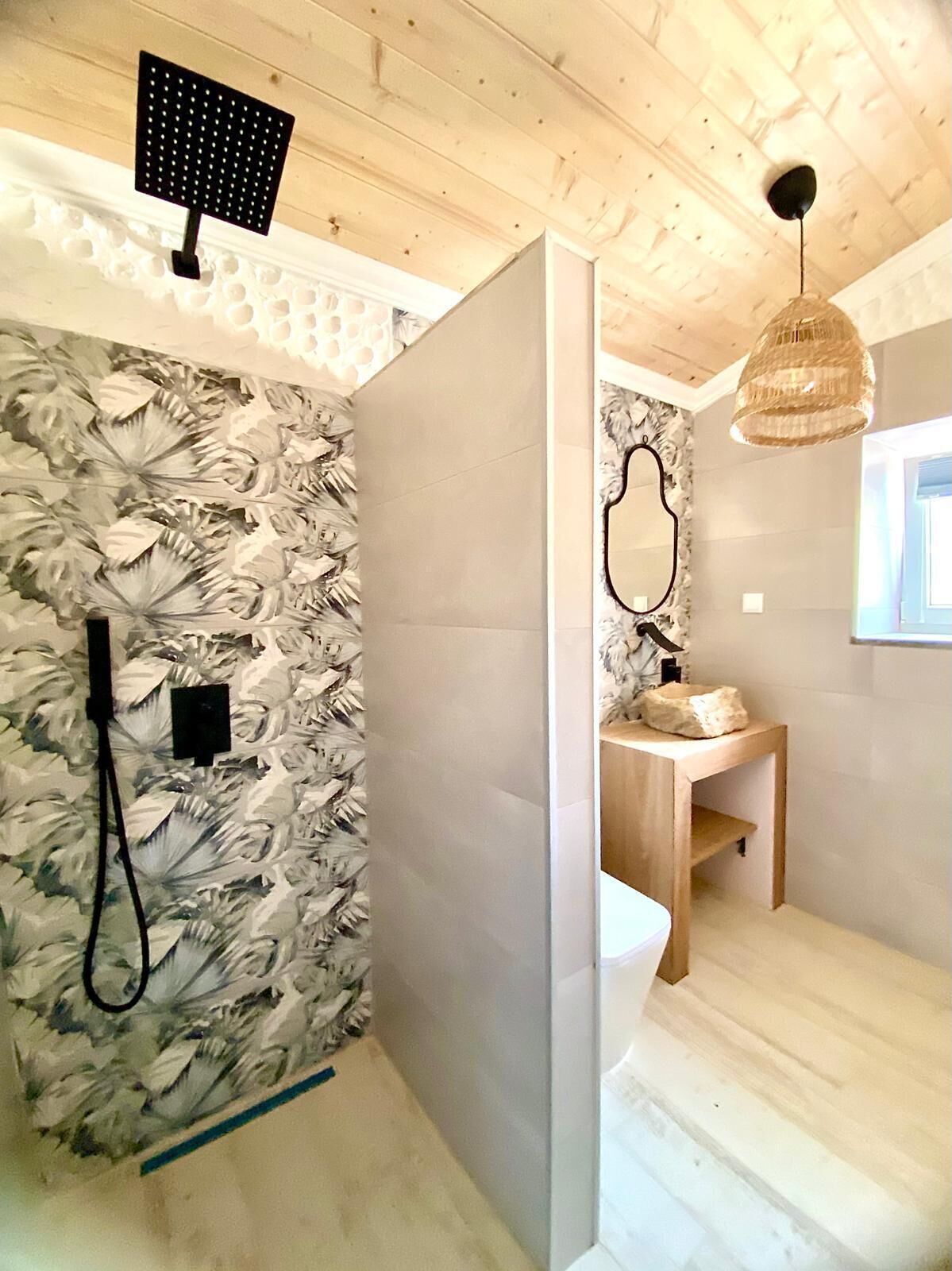 Une salle de bain avec un plafond en bois, un espace douche, un meuble-lavabo avec un miroir et un luminaire suspendu.