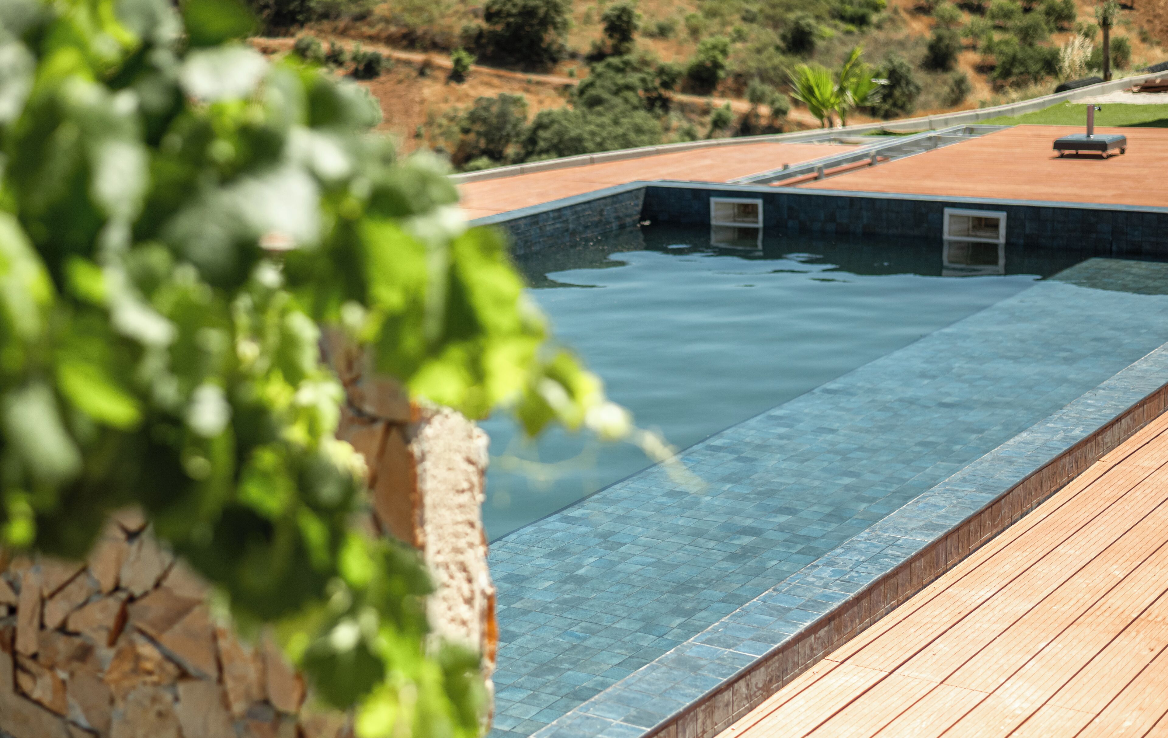 Una piscina con muelle de madera y pared de piedra.