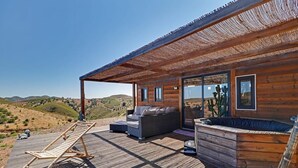 Une cabane en bois dotée d’une terrasse, d’un canapé, d’un fauteuil et d’un bain à remous.