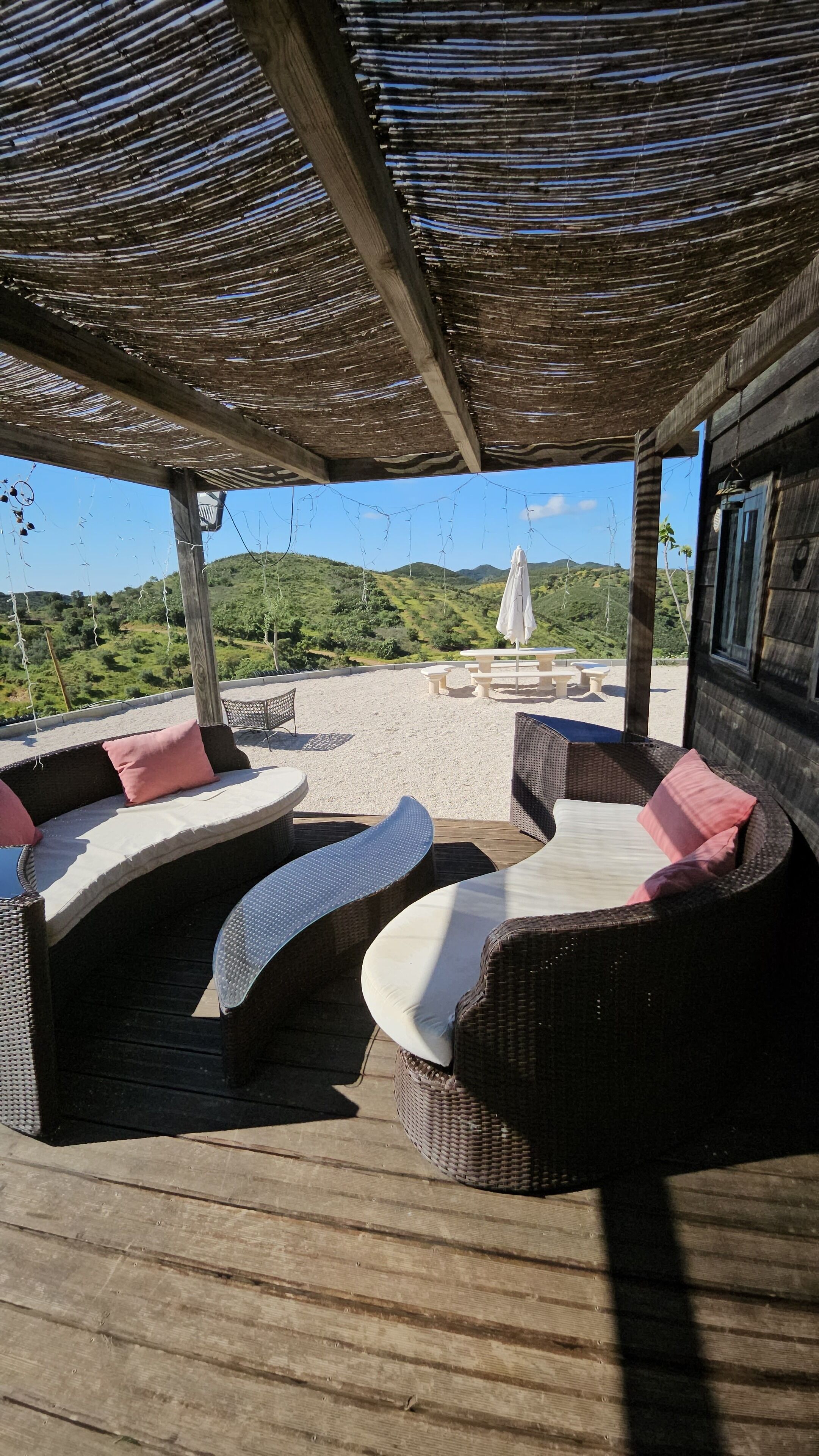 An outdoor seating area with wicker furniture and a view of green hills.