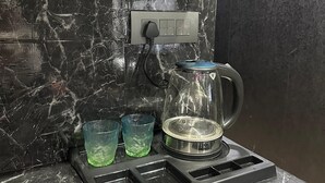 A kitchen with a black marble backsplash, a kettle on a stove, and two green glasses on the counter. - Villa Vistosa Gomti Nagar (Lucknow)