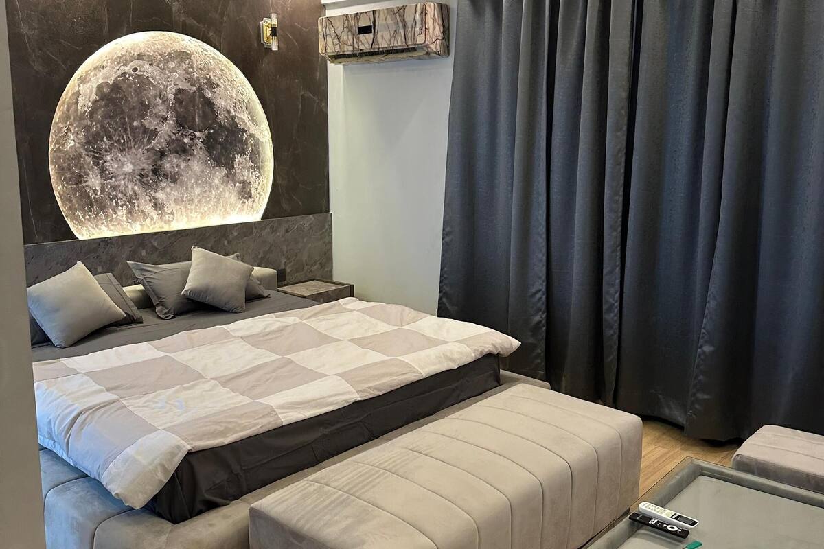 Un dormitorio moderno con una cama grande, un ventilador de techo y un equipo de aire acondicionado instalado en la pared.