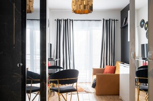 Una sala de estar moderna con un sofá, sillas, una mesa de comedor y un ventanal con cortinas.