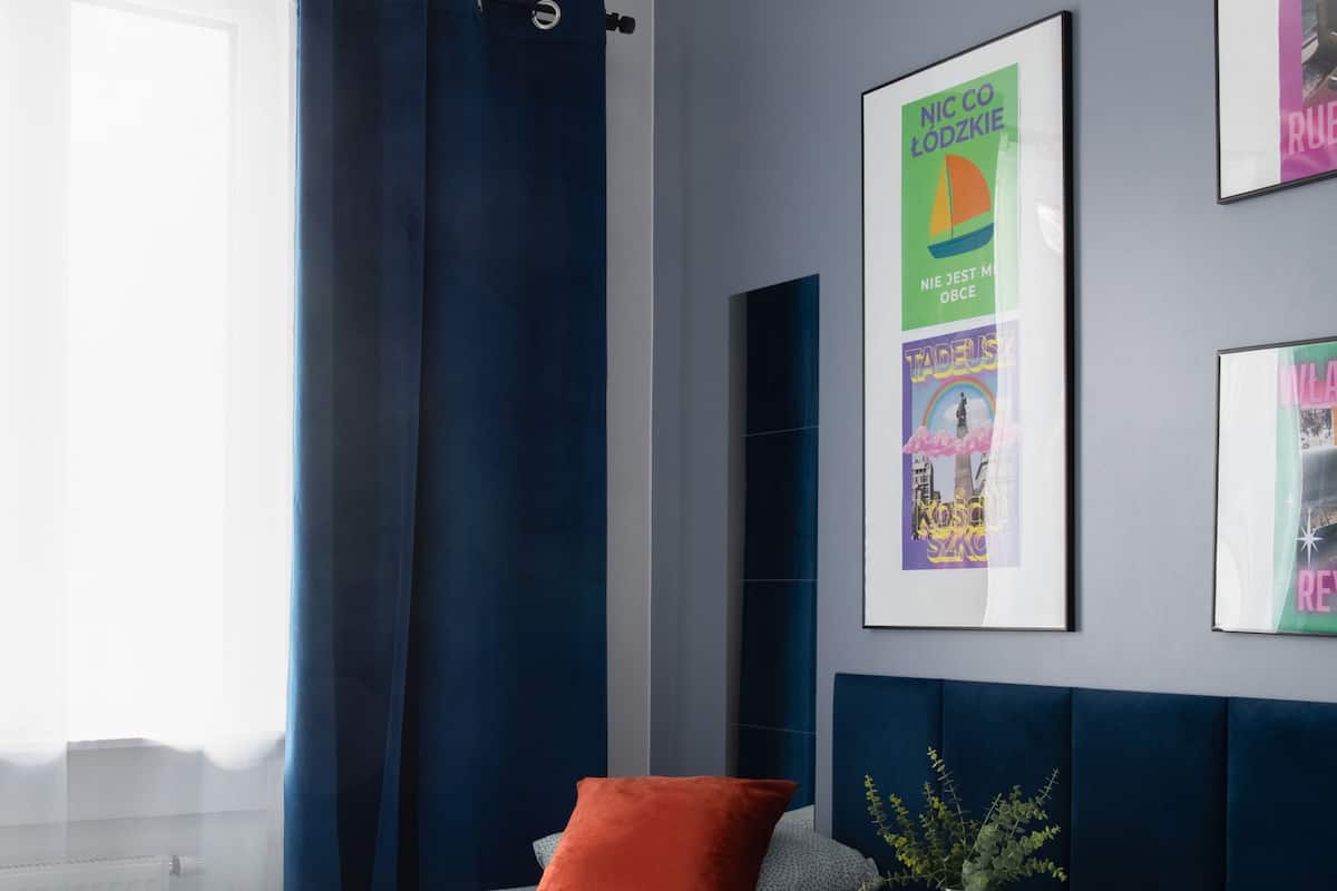 A hotel room with two beds, a window with curtains, and wall art.