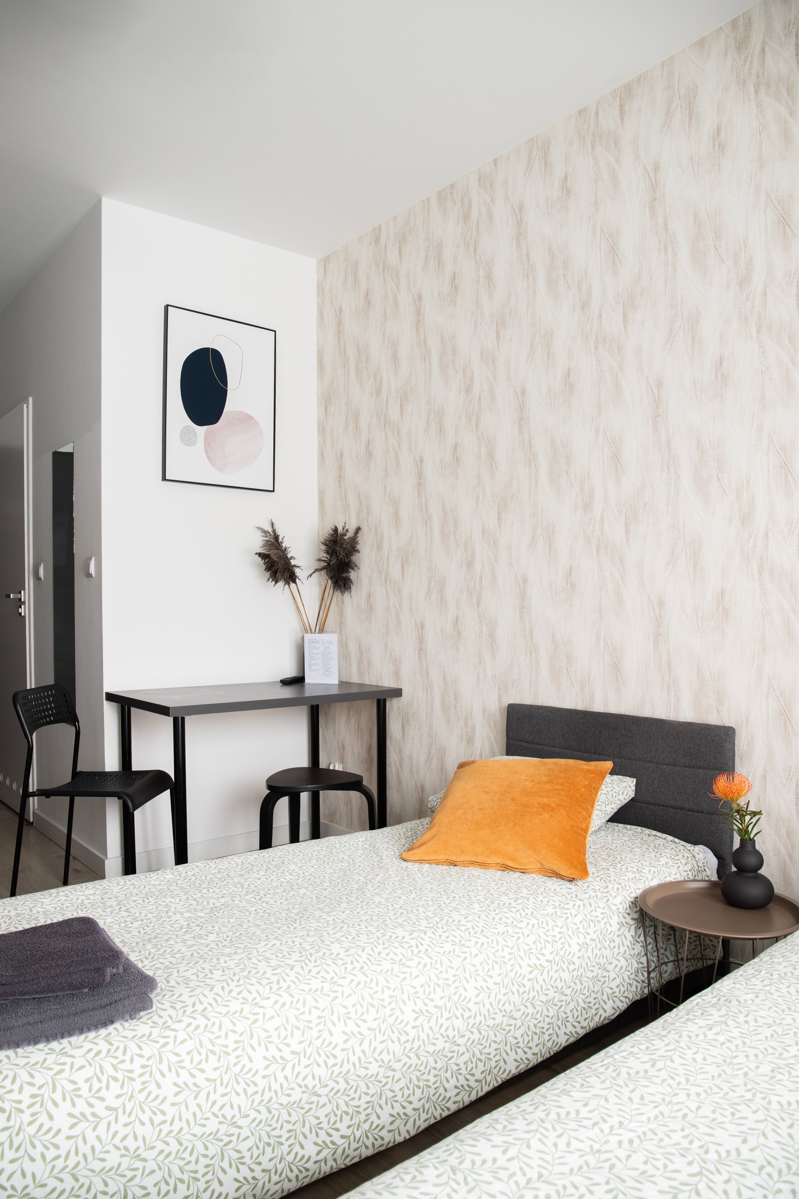 Una camera da letto moderna con un letto, un comodino e una scrivania con sedie.