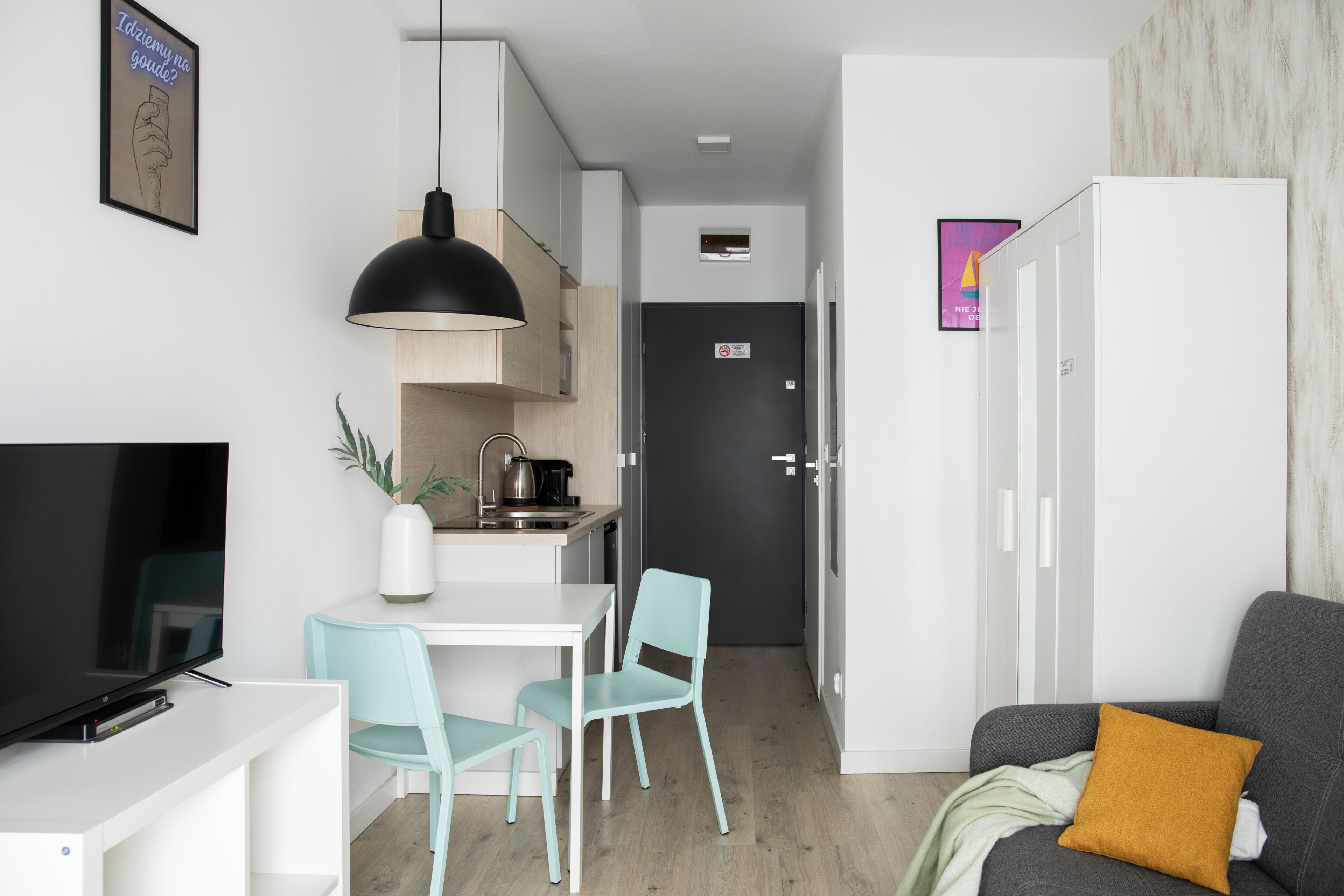 Un salon moderne comprenant un téléviseur, un canapé et un coin repas avec des chaises et une table.