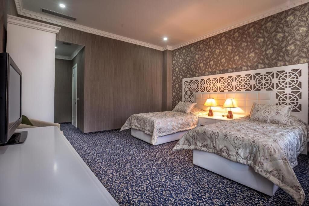 A hotel room with two beds, a TV, and a desk.