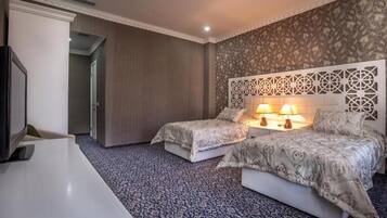A hotel room with two beds, a TV, and a desk.