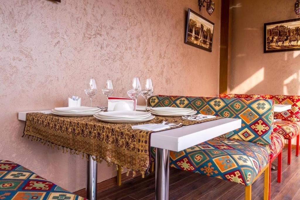 A dining area with a table set for four, a patterned sofa, and wall-mounted artwork.