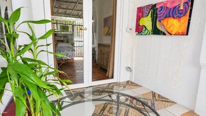A room with a glass table, a potted plant, a painting, and a patterned floor. - Salo Casa Verde Studio (San Juan)