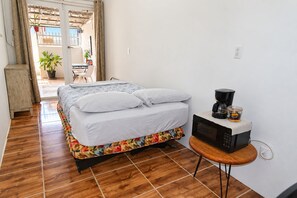 A bedroom with a bed, a coffee maker, and a small table.