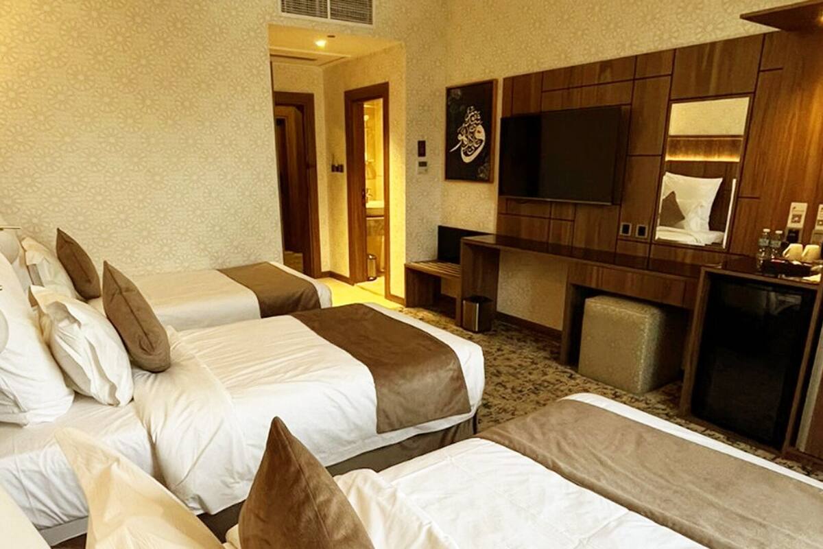 Een hotelkamer met twee bedden, een televisie, een bureau en een spiegel.