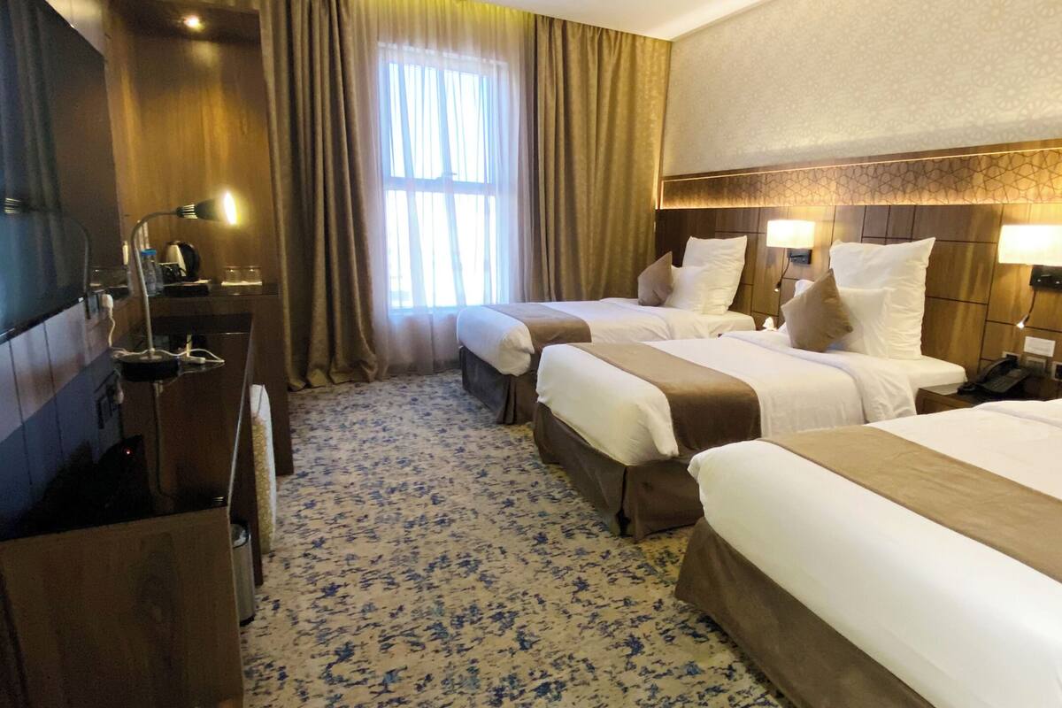 Een hotelkamer met twee bedden, een televisie, een bureau en een raam met gordijnen.
