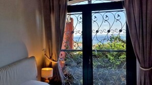 A bedroom with a bed, a nightstand, a lamp, and a window with curtains. - Exceptional villa with panoramic sea views AV 81 (ROSES)