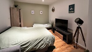 Une chambre avec deux lits, une télévision et un trépied.