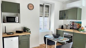 Une cuisine compacte équipée d’un four à micro-ondes, d’un petit réfrigérateur et d’un coin repas avec une table et des chaises.