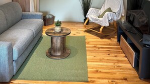 Un salon avec un canapé gris, une table basse ronde, un plancher en bois, un meuble pour la télévision et un globe terrestre fixé au mur.