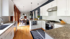 A modern kitchen with white cabinets, a central island, stainless steel appliances, and a black and white striped rug.
