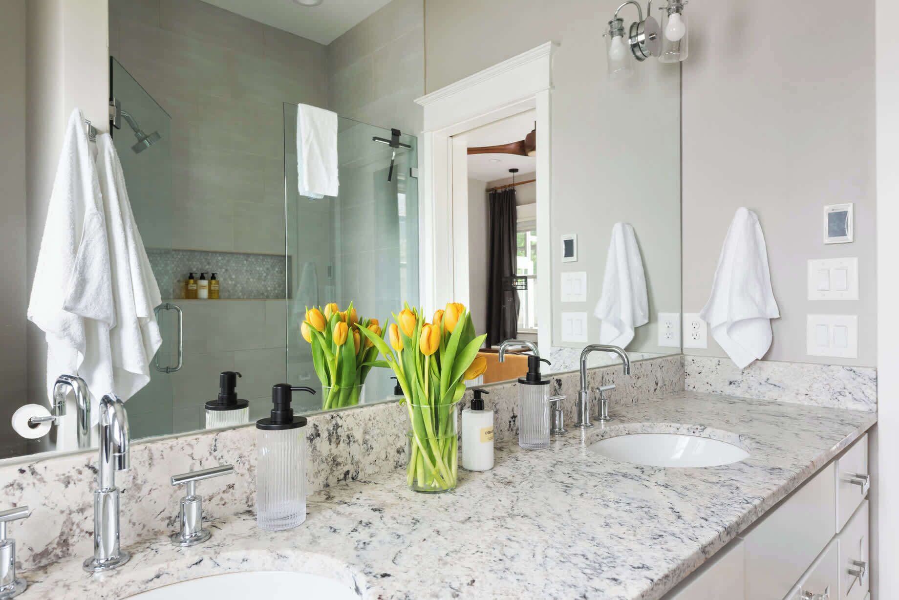 Ein modernes Badezimmer mit zwei Waschbecken, einer Glasdusche und einem Spiegel.