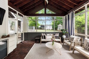 A cozy room with a large window, a wooden ceiling, and a view of a house and trees. - Canvas Haven (Atlanta)