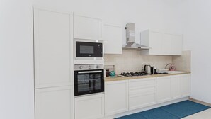 A modern kitchen with white cabinetry, a built-in oven, a microwave, a gas stove, and a stainless steel range hood.