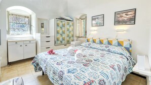 Un dormitorio con cama, cómoda, armario, ventana y candelabro.