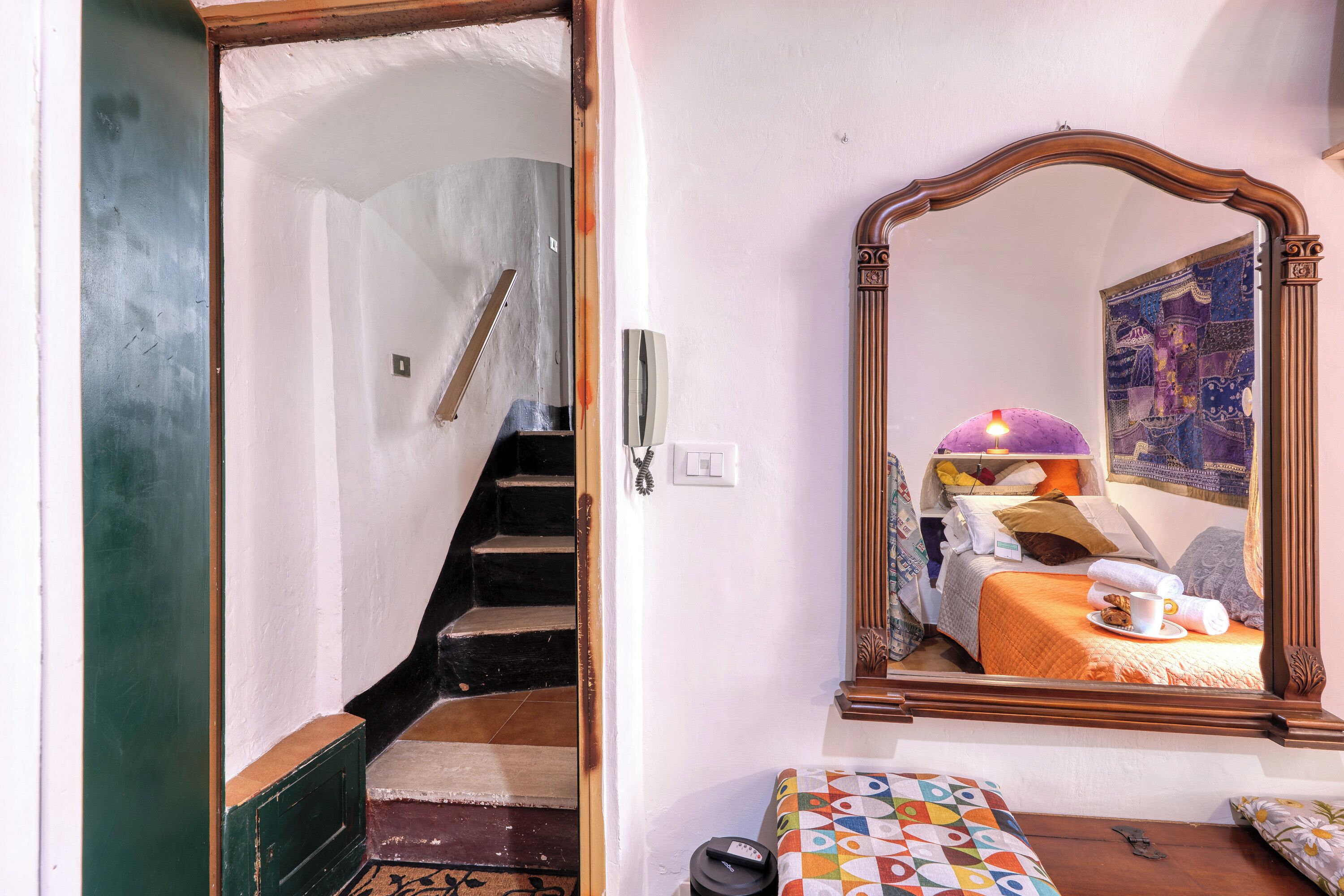 Ein Schlafzimmer mit einem Bett, einem Spiegel, einer Treppe und einer Tür.