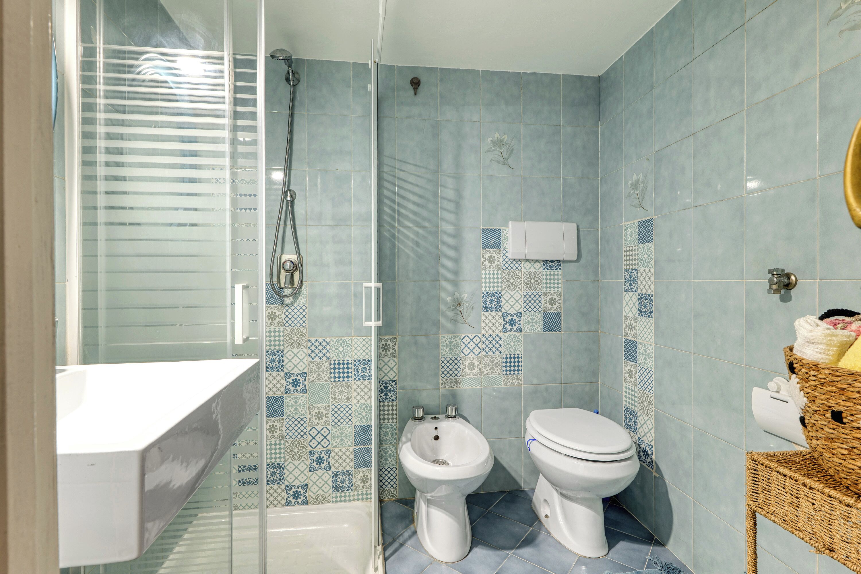Une salle de bain équipée d’une douche, d’un bidet, de toilettes et d’un espace douche séparé par des parois en verre.