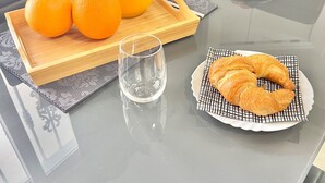 A breakfast table with a pitcher of orange juice, two oranges, a croissant, and two glasses. - Casa Yei - Stay by the sea! (Puerto del Carmen)