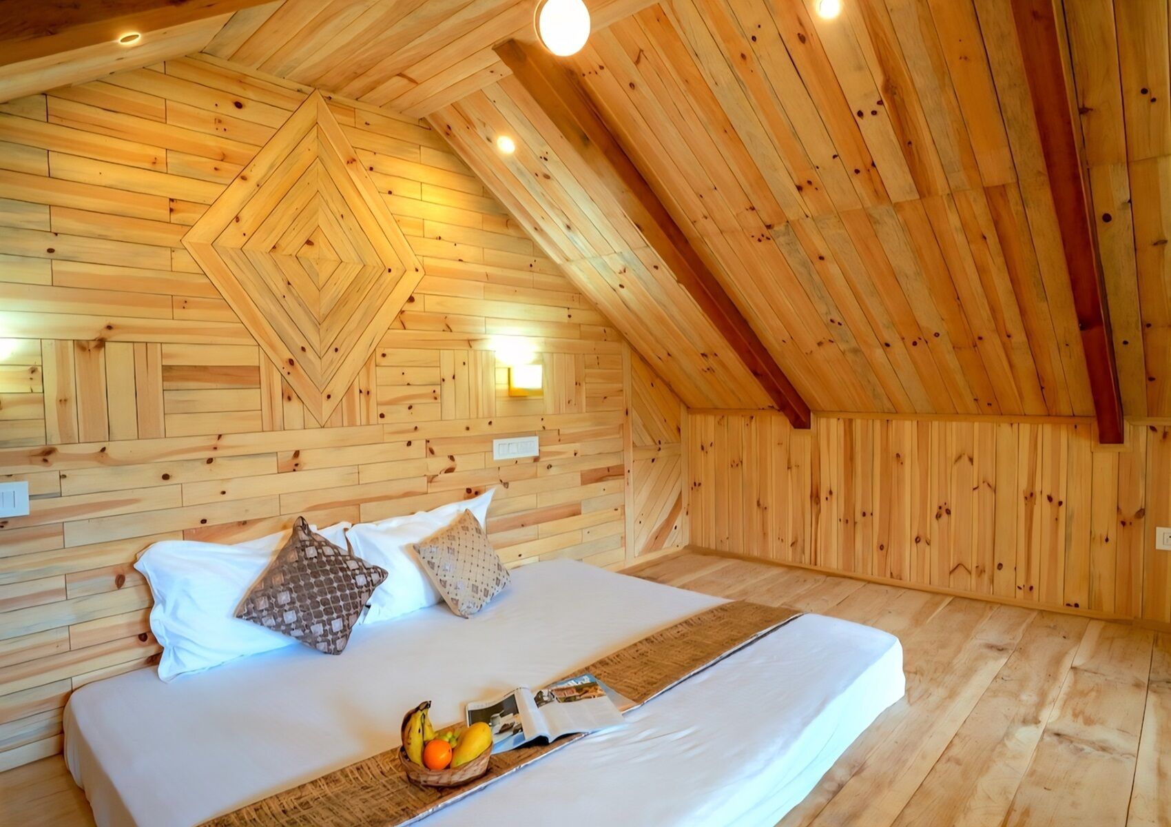A wooden-paneled room with a bed, pillows, and a tray with fruits and a magazine.