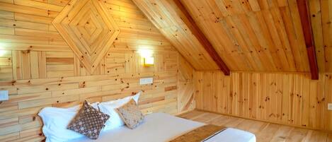 A wooden-paneled room with a bed, pillows, and a tray with fruits and a magazine.