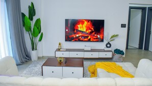 A modern living room with a flat-screen TV, white sofa, and a coffee table.