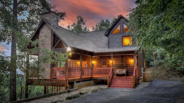 A rustic cabin with a wooden deck and a staircase leading to the entrance.