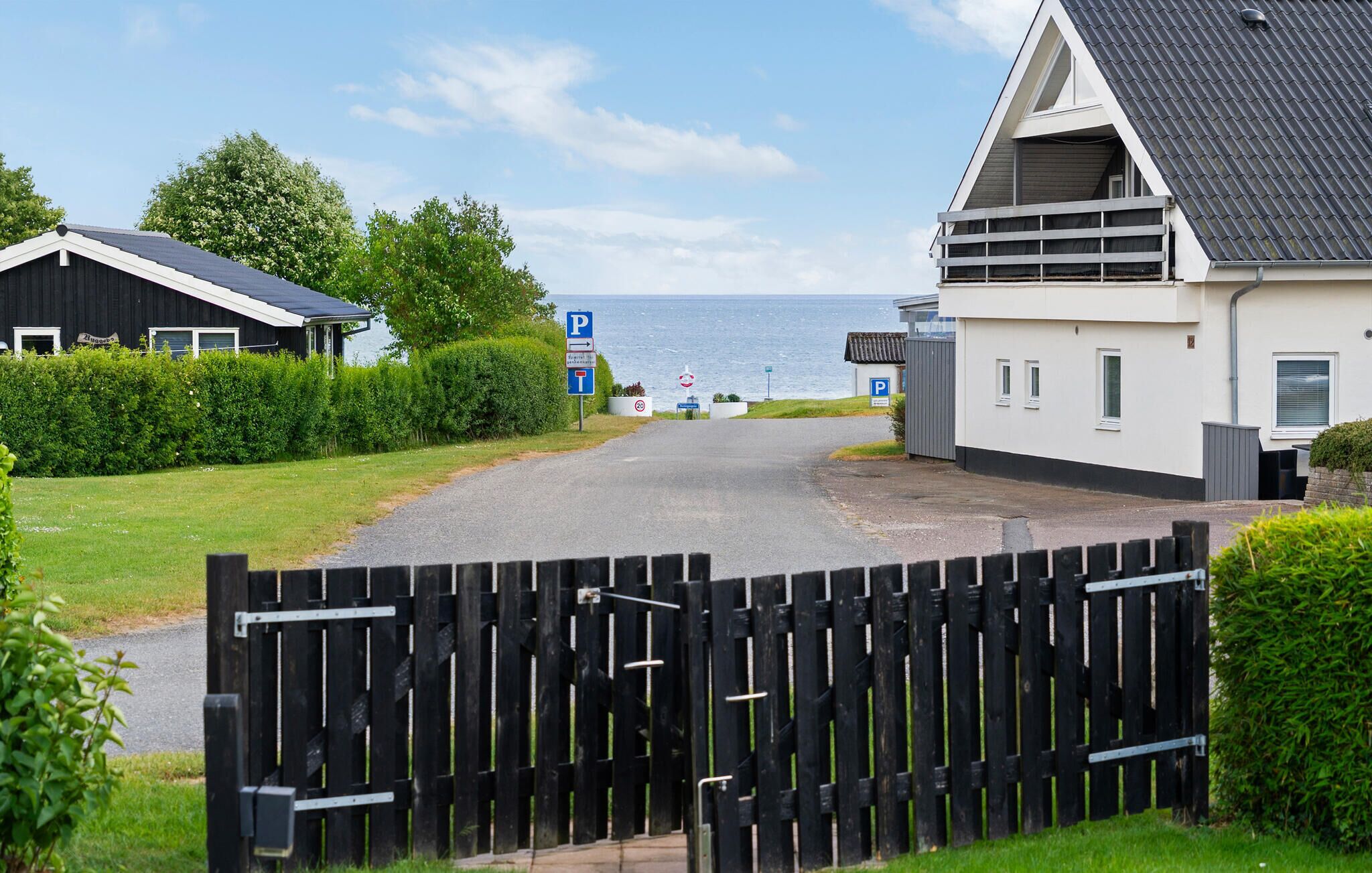 A coastal property with a gated entrance, a parking area, and a view of the sea.